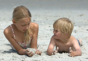 Sister and brother playing on the beach, the boy has Downs Syndrom