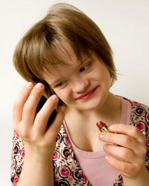 Teenage girl with downs syndrome putting on makeup.