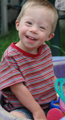 Young Down syndrome boy playing in sandpit