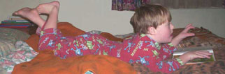 Jacob looking at books and watching TV at age 6 years - Down Syndrome doesn't stop normal development, but social attitudes do.